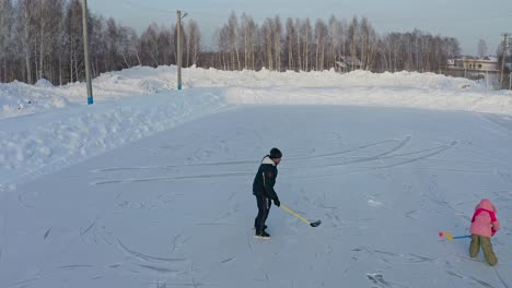 Mann-Und-Kind-Spielen-Hockey-Auf-Dem-Zugefrorenen-See