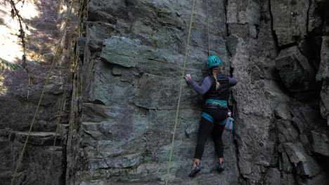Abenteuerlustige-Frau-In-Sicherheitsausrüstung-Klettert-Auf-Einen-Felsen
