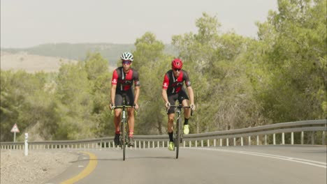 slow-motion-of-professional-Young-Men-Cycling-On-Road-Bike-Outside-On-Desert-Road
