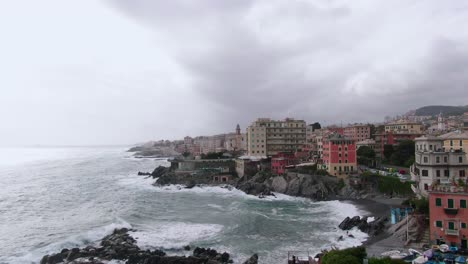 Rocky-coastline-with-mighty-sea-hitting-coast-of-Genoa-city,-drone-ascend-view
