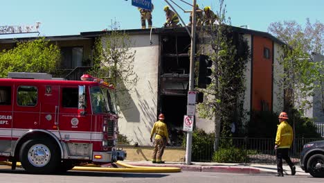 Firefighters-cutting-a-roof,-trying-to-get-inside-a-burnt-building-in-Los-Angeles,-USA