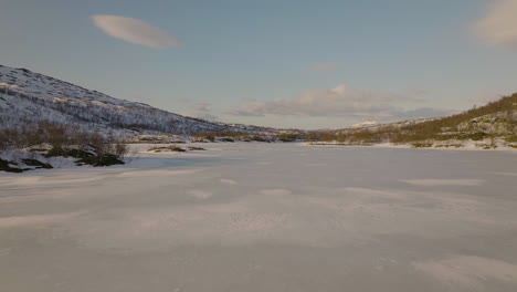 Aerial-over-white-winter-landscape-in-arctic,-frozen-lake-of-Skogsfjordvatnet