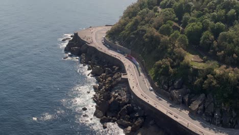 Beautiful-coastal-road-on-rocky-cliffside,-tropical-coastline,-aerial-drone-view