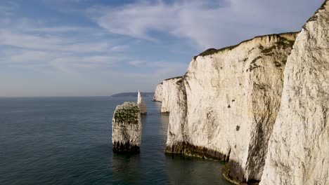 Drone-flying-between-stack-and-rocky-cliff-wall-of-Old-Harry-Rocks,-Dorset