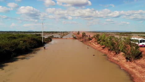 Río-O-Canal-A-Lo-Largo-De-La-Carretera-Naranja-En-Camboya,-Vista-Aérea-De-Drones