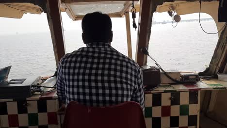 A-boat-driver-on-the-top-deck-of-a-tourist-ferry-from-Mumbai-to-Elephanta-island,-near-Mumbai-India