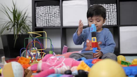 Zwei-Jahre-Alter-Mexikanischer-Junge,-Der-Mit-Didaktischem-Spielzeug-Im-Unordentlichen-Wohnzimmer-Spielt