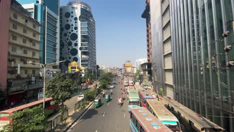 Belebte-Straße-In-Dhaka-Mit-Bussen-Und-Autorikschas-An-Sonnigen-Tagen