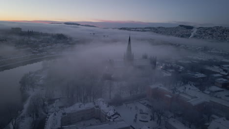 Nidaros-Cathedral,-Nidarosdomen-Obscure-With-Fog-And-Clouds-At-Sunrise-In-Trondheim-City,-Norway