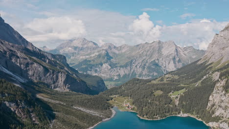 Circling-cinematic-establishing-drone-shot-over-Blue-Lake-Oeschinen-towards-Kandersteg-Swiss-mountains
