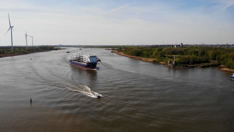 Aerial-View-Of-Symphony-Provider-Cargo-Ship-Approaching-River-Bend-On-Oude-Maas-In-Barendrecht-With-Speedboat-Passing-By