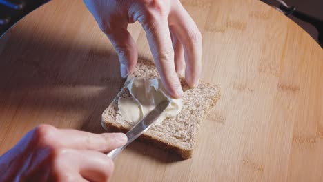 Hands-Spread-Creamy-Cheese-Triangle-On-Whole-Wheat-Bread