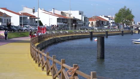 People-siting-at-cafe-by-Ria-de-Aveiro,-Torreira,-Portugal,-on-a-sunny-windy-day