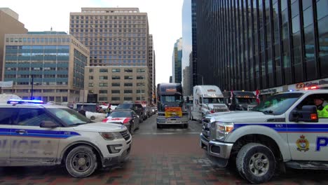 Langsames-Vorbeifahren-Zwischen-Zwei-örtlichen-Polizeifahrzeugen,-Trucker-Protestiert-Gegen-Covid-19-Mandate-In-Ottawa,-Ontario,-Kanada