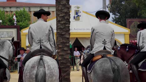 Spanish-men-sit-on-horses-outside-the-Real-Escuela-Andaluza-de-Del-Arte-Ecuestre-caseta-in-Jerez-de-la-Frontera,-Spain