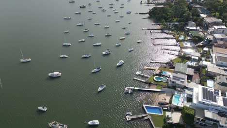Aerial-fly-over-suburban-waterfront-home,-houses,-neighborhood-properties-with-boats,-yacht,-sailboat-marina-and-wharf