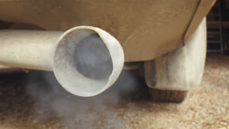 Tracking-probe-lens-shot-of-old-car-exhaust-pipe-from-which-smoke-and-fumes-are-pouring
