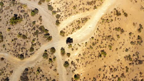 Aerial-view-following-a-car-driving-on-a-desert-road,-in-sunny-Arizona,-USA---rotating,-top-down,-drone-shot