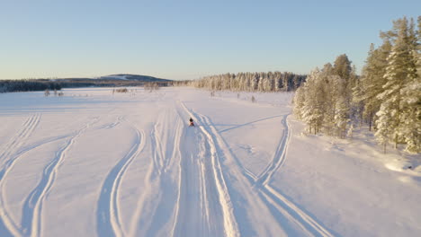 Aerial-view-above-three-snowmobiles-riding-across-snowy-Lapland-Sweden-wilderness-trail