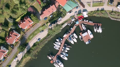 Drone-flyover-top-shot-aerial-bird-view-of-tiny-boats,-ships-and-private-yachts-in-the-new-harbour-of-Mikolajki-in-Poland-on-the-Mikolajskie-lake---Most-famous-tourist-destination