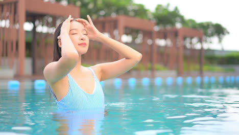 Young-Sexy-Slender-Woman-Caresses-Her-Wet-Hair-After-Swim-in-Swimming-Pool-of-Tropical-Resort,-Slow-Motion