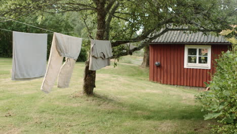 Laundry-drying-in-the-sun-on-drying-line-in-front-of-swedish-farmhouse