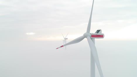 Luftaufnahme-Von-Windmühlenturbinen-über-Einer-Schicht-Aus-Dichtem-Nebel,-Die-Grüne,-Saubere-Energie-Erzeugen