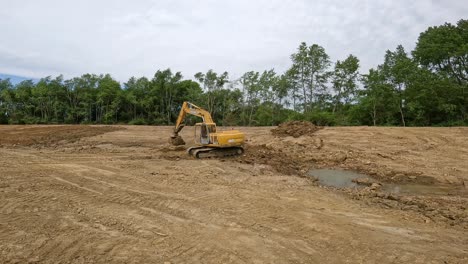 Deere-Hydraulic-excavator-tamping-dirt-on-the-bottom-of-pond-at-a-land-development-site
