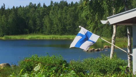 Bandera-De-Finlandia-Ondeando-En-La-Cabaña-De-Verano,-Ambiente-De-Vacaciones