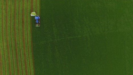 Aerial-view-of-a-tractor-cutting-the-grass-in-a-large-green-field