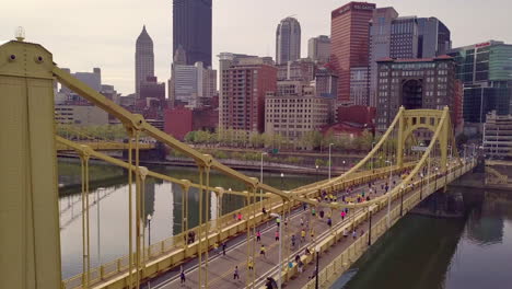 Aerial-fly-over-shot-of-runners-crossing-bridge,-Pittsburgh-Marathon