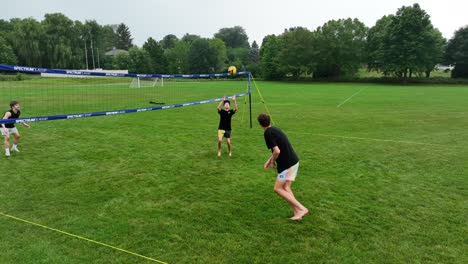 White-teenagers-playing-grass-volleyball-in-park