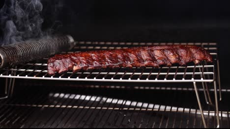 A-low-angle-pan-of-smoking-pork-baby-back-ribs-run-and-sauce