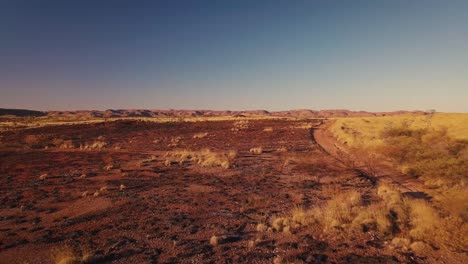 Drone-Aéreo-Bajo-Siguiendo-Un-Camión-4wd-Por-Un-Camino-De-Grava-En-El-Desierto-Australiano-Después-De-Un-Incendio-Forestal