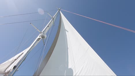 Looking-up-on-a-white-sail-on-a-boat-against-a-clear-blue-sky