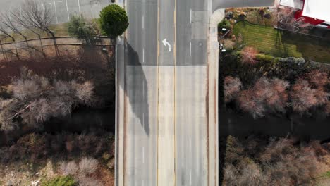 Aerial-shot-zooming-down-on-vehicles-traveling-on-creek-overpass-in-California