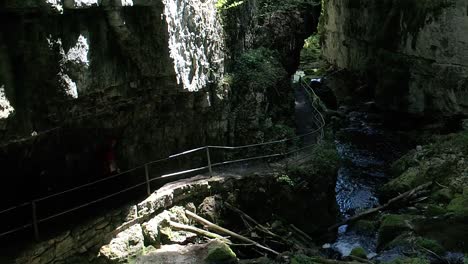 Vista-Aérea-Del-Sendero-Dentro-De-Una-Cueva-Del-Cañón,-Gente-Caminando-Sendero-Peligroso,-Suiza