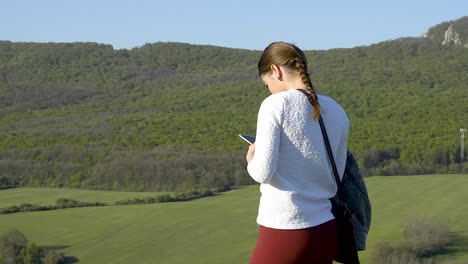 Junge-Frau-Tippt-Auf-Ihrem-Mobiltelefon-In-Der-Wunderschönen-Grünen-Landschaft