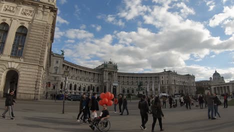 Man-on-a-wheelchair-with-orange-ballons-in-Vienna