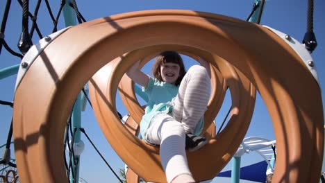Young-girl-climbing-through-playground-rings-smiling-on-sunny-day