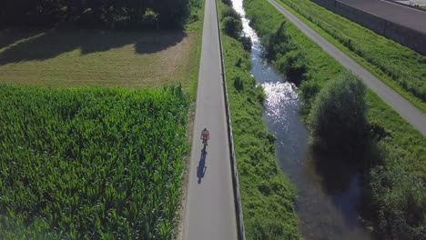 Aerial-panoramic-view-in-Sugana-Valley,-Italy-with-drone-static-and-tilting-down-as-biker-rides