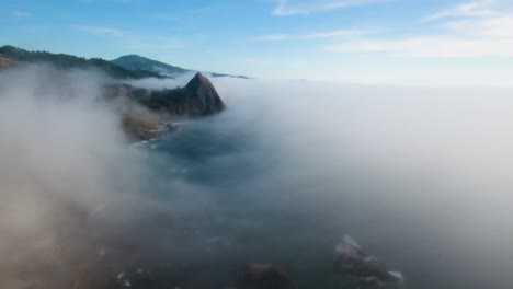AERIAL:-Pushing-through-a-mist-filled-day-towards-a-mountain-on-the-Oregon-coastline