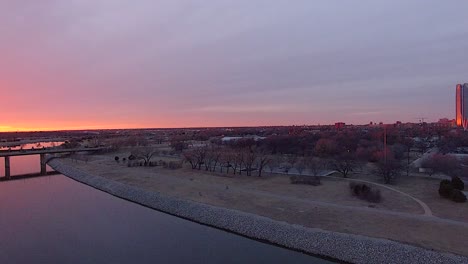 Rotierende-Enthüllung-Eines-Sonnenuntergangs-über-Dem-Oklahoma-River-Mit-Der-Skyline-Der-Stadt-Oklahoma