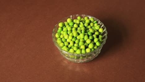 A-bowl-of-green-peas-placed-on-a-brown-background