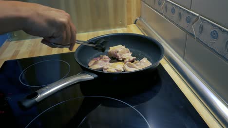 A-man´s-arms-turning-around-a-chicken-drumsticks-fillets-in-a-pan