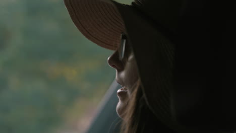 Close-up-of-woman-wearing-sunhat-in-car-as-car-drives-in-slow-motion
