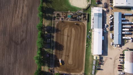 Aerial-of-water-truck-wetting-down-the-dirt-area-in-an-effort-to-keep-down-the-dust-as-horses-and-riders-workout-just-feet-away,-Kansas,-Missouri