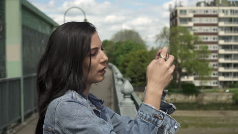 Attractive-Latina-tourist-concentrating-while-taking-a-picture-of-London-from-a-bridge-while-holding-her-phone-to-frame-the-shot