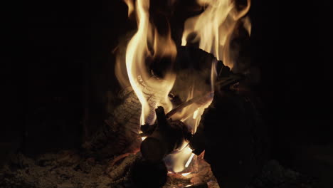 4K-close-up-clip-of-a-dark-and-warm-wood-fire-burning-inside-a-traditional-rural-black-fireplace-in-a-winter-house