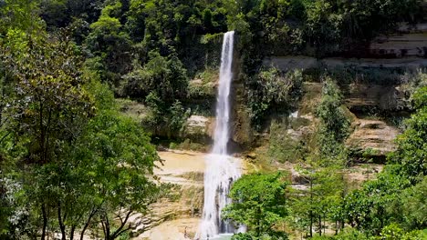 Ein-Wunderschöner-Wasserfall-Stürzt-Eine-Klippe-Hinunter-In-Einen-Wunderschönen-Türkisfarbenen-Pool-Inmitten-Eines-üppigen-Grünen-Dschungels-In-Bohol,-Philippinen,-Während-Die-Einheimischen-Das-Kühle,-Entspannende-Wasser-Genießen